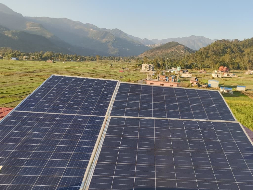Solar panels on a roof with mountains in the background.